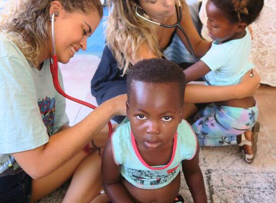 Two Volunteers doing a health screen of the children at the kindergarten