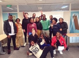 15 Students standing in front of a white board looking happy