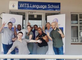 Group of teachers standing in front of a Wits Language School sign