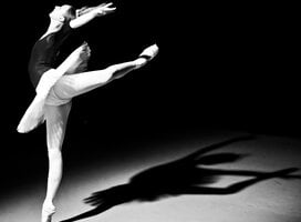 Black and white photo of a ballerina with her leg in attitude position.