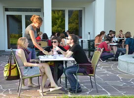 Participants sitting around tables on the terrace and talking