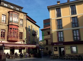 Two orange-toned, sunlit buildings with cafes at the bottom