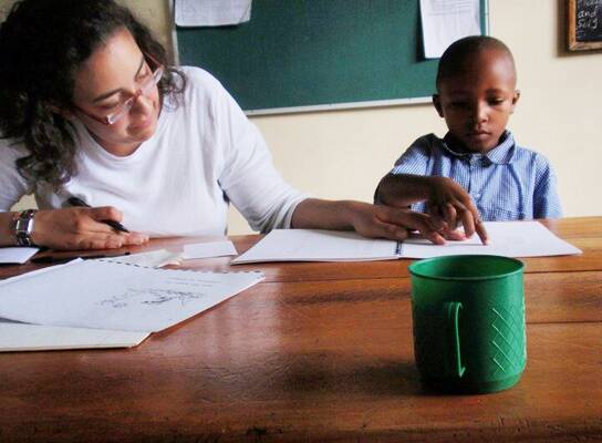 Volunteer in Tanzania helping a student with a reading assessment 