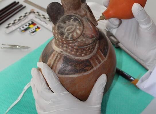 Cleaning a Moche ceramic vessel