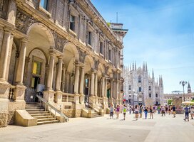 People walk by a tall stone building 