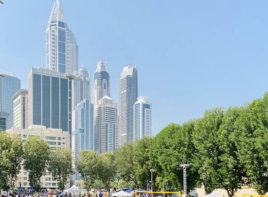Students on the green AUD campus with the Dubai skyline in the background.
