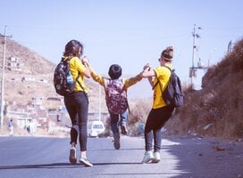 two volunteers and one of the kids jumping on the street