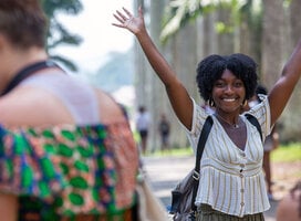 A smiling student with her hands in the air