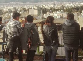 A group of students lined up a long a fence look at the view before them in Athens, Greece