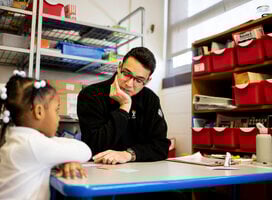 Tutor sitting at table with student looking at student