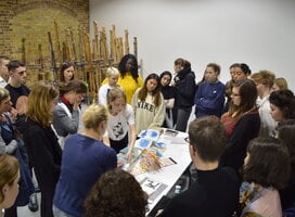 Group of young students gathered around a painting