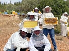 students in protective clothing showing off beekeeping