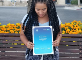 Woman with long black twists looking down at a certificate she's holding up to the camera
