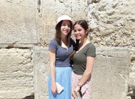 Two women stand in front of the Western Wall