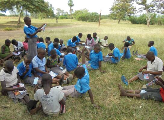 A girl child leading the rest of the children to read and concentrate on what took them to school.