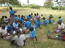 A girl child leading the rest of the children to read and concentrate on what took them to school.