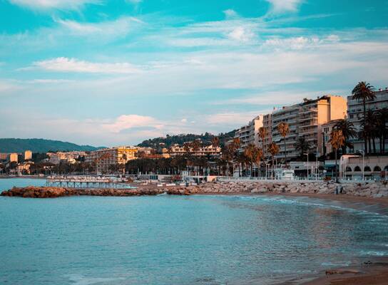 A sunny beach with houses rising along it