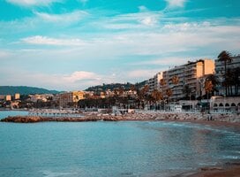 A sunny beach with houses rising along it
