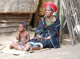 A maasai women sitting outside with her child 