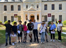 Group of diverse male and female students standing in front of university building