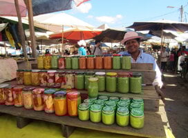A person standing in front of a stall of jars filled with sauces and vegetables.