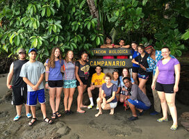 Students posing in front of a sign that reads "Estacion Biologica Campanario"