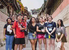 Students taking a group photo on steps in between two buildings