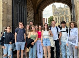 Group of a dozen students standing in an archway of a historic building in France