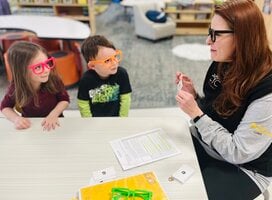 Early Learning Corps member supporting 2 students at a desk