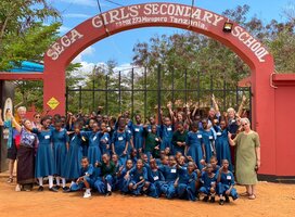 2023 volunteer group and students under SEGA School sign 