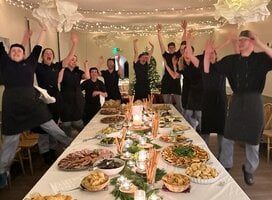 Kitchen team standing around table full of food