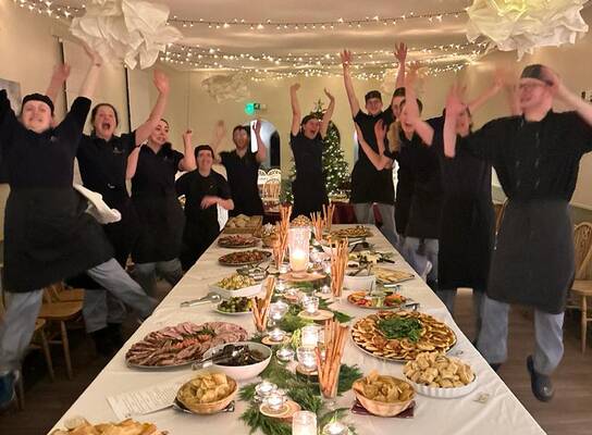 Kitchen team standing around table full of food