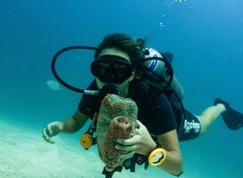 a scuba diver holds trash 