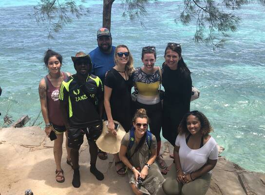 A group of students posing in front of a body of water.