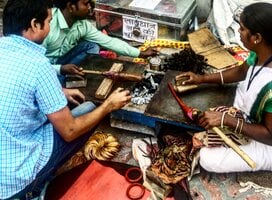 Three people making tools over coals