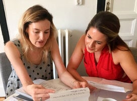 Two women sitting in a classroom studying together. 