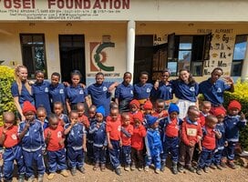 Teachers, volunteers and students posing in front of the school
