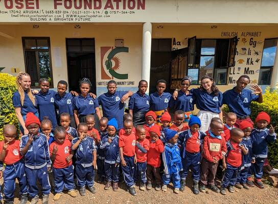 Teachers, volunteers and students posing in front of the school