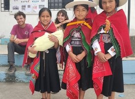 Image of three Kichwa girls wearing their traditional clothing and two volunteers smiling