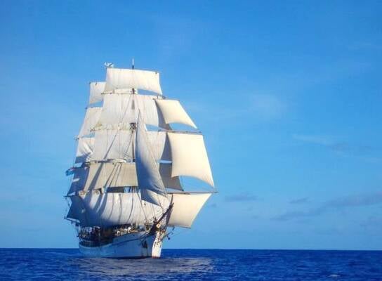 A tall ship with all sails up in the open ocean