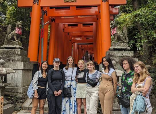 group smiling in front or red gate