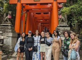 group smiling in front or red gate