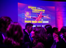 Students mingle in front of a screen showing the slide "Sports Tomorrow Congress"
