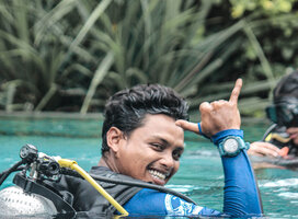 Dive instructor in a swimming pool giving the "that rocks" signal