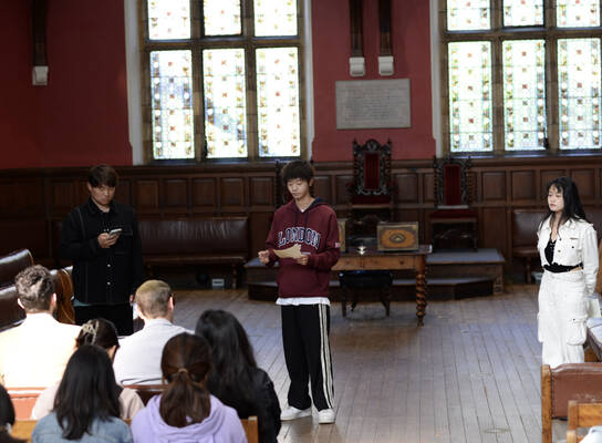Three students presenting in the Oxford Union