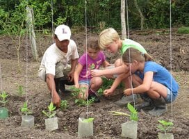 woman taking care of a vegetable garden with 3 children