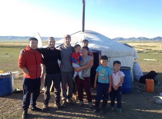 Volunteers and nomads are standing in front of the Mongolian traditional dwelling.