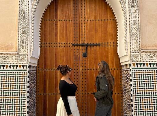 Two students standing in front of a wooden, carved door in the Medina