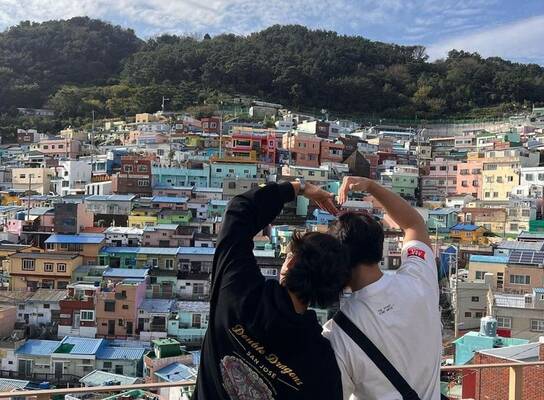 Students making heart hands over Busan skyline