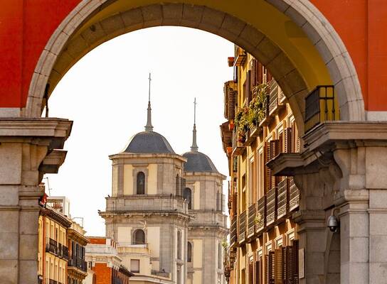 Red archway looking out on historic building in Spain